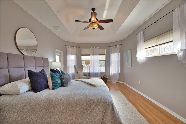 bedroom featuring hardwood / wood-style flooring, a raised ceiling, and ceiling fan