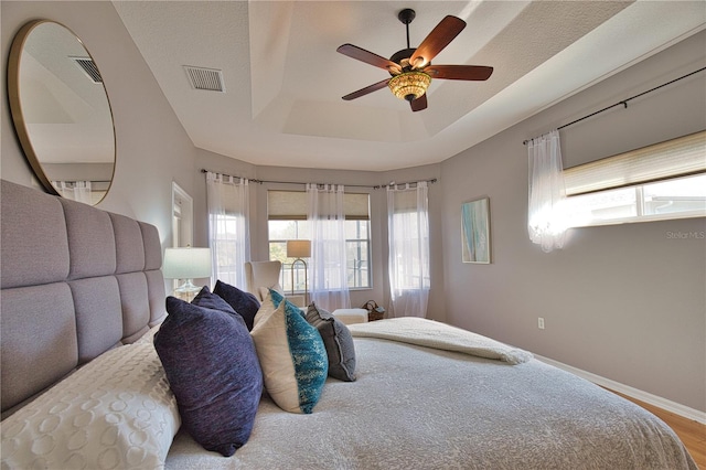 bedroom featuring hardwood / wood-style floors, ceiling fan, and a tray ceiling