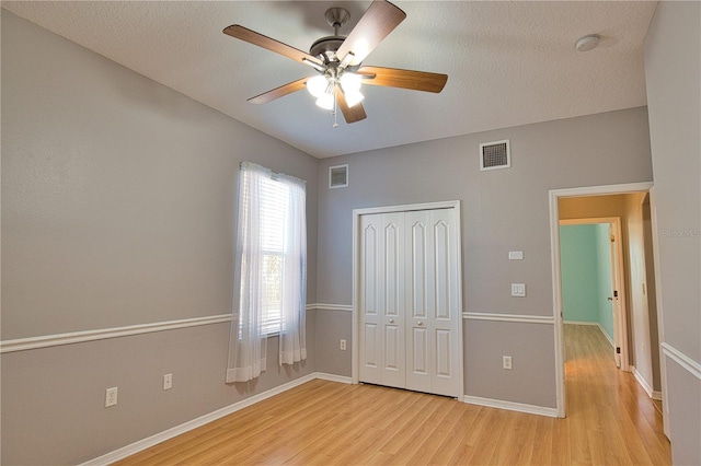 unfurnished bedroom with ceiling fan, light hardwood / wood-style floors, a closet, and a textured ceiling