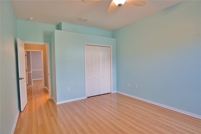 unfurnished bedroom featuring ceiling fan, light hardwood / wood-style floors, and a closet