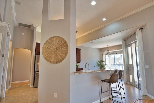 kitchen featuring sink, crown molding, a breakfast bar area, stainless steel fridge, and kitchen peninsula