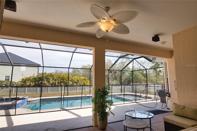 view of pool with an in ground hot tub, ceiling fan, a patio, and glass enclosure