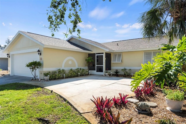 single story home featuring a garage, concrete driveway, stucco siding, roof with shingles, and a front yard