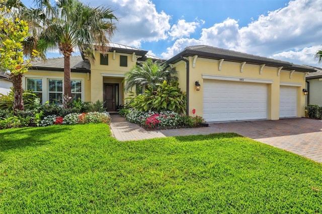 view of front of property with a garage, a front yard, decorative driveway, and stucco siding