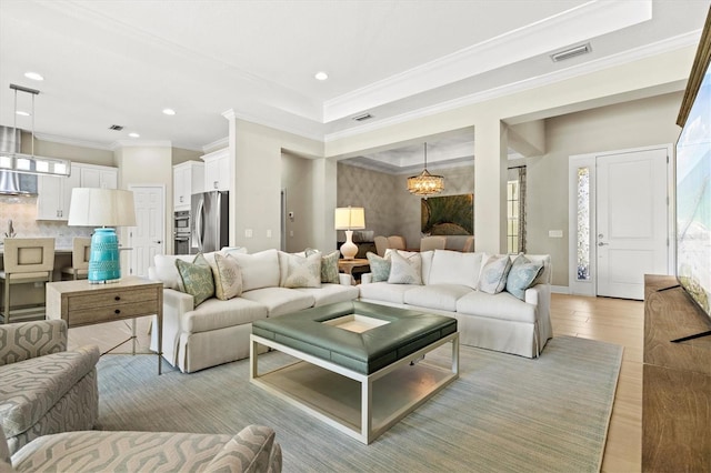 living area with recessed lighting, a notable chandelier, visible vents, ornamental molding, and light wood-type flooring