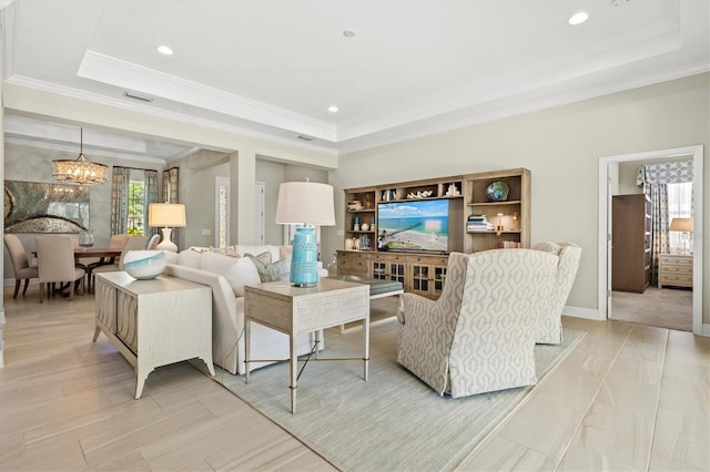 living area with ornamental molding, a tray ceiling, and a chandelier