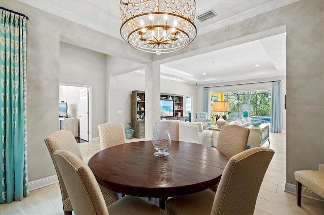 dining area featuring an inviting chandelier, visible vents, a raised ceiling, and ornamental molding