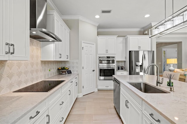 kitchen with a sink, visible vents, white cabinetry, wall chimney range hood, and appliances with stainless steel finishes