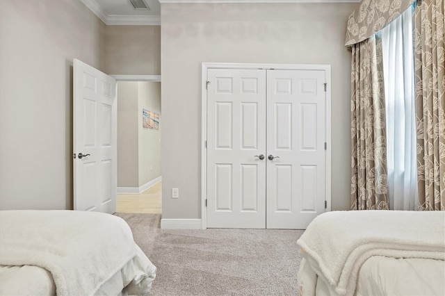 bedroom with baseboards, visible vents, ornamental molding, carpet flooring, and a closet