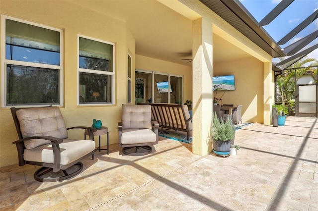 view of patio with glass enclosure and a ceiling fan