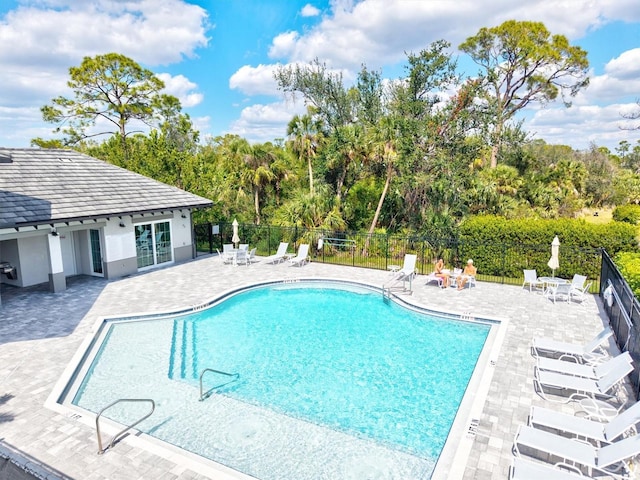 pool with a patio area and fence