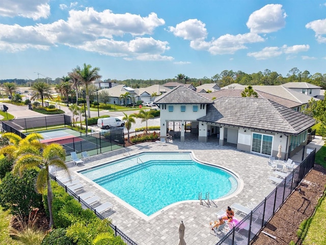 community pool with a patio area, a residential view, and fence