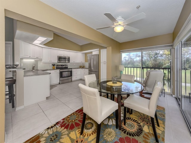 dining area with light tile patterned flooring, vaulted ceiling, and ceiling fan