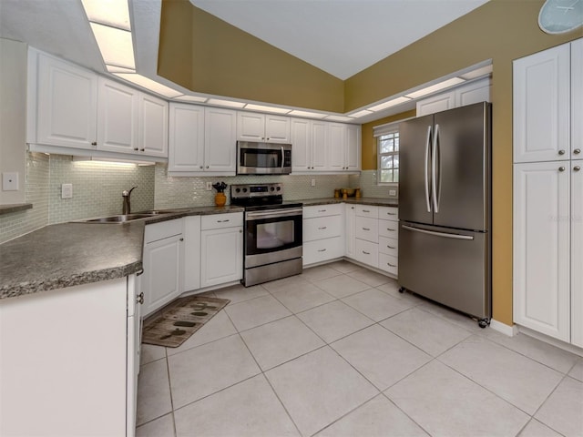 kitchen with appliances with stainless steel finishes, lofted ceiling, sink, white cabinets, and light tile patterned floors