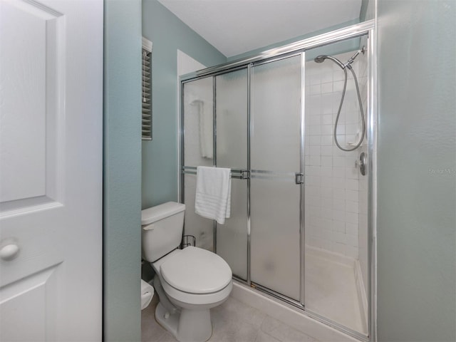 bathroom with a shower with door, tile patterned flooring, and toilet