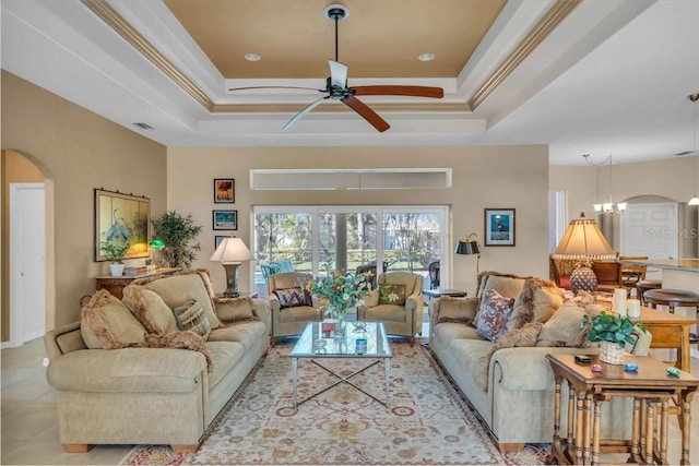 living room featuring crown molding, a raised ceiling, ceiling fan with notable chandelier, and light tile patterned floors