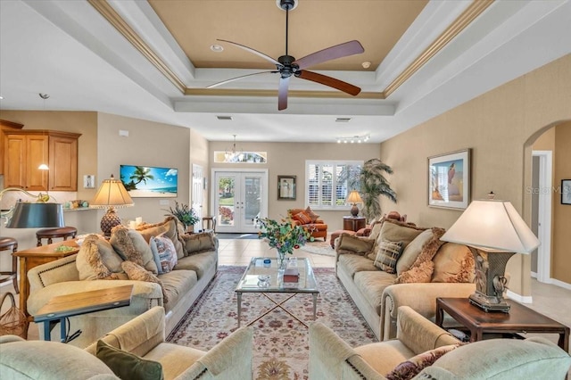 living room featuring a tray ceiling, ornamental molding, french doors, and light tile patterned flooring