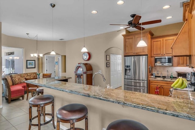 kitchen with tasteful backsplash, stainless steel appliances, kitchen peninsula, and hanging light fixtures