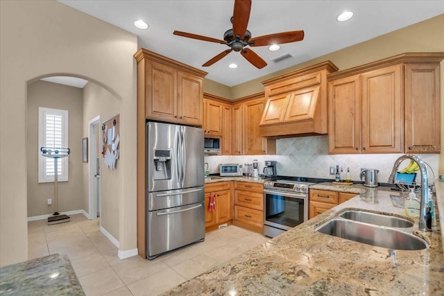 kitchen featuring sink, custom exhaust hood, tasteful backsplash, appliances with stainless steel finishes, and light stone countertops