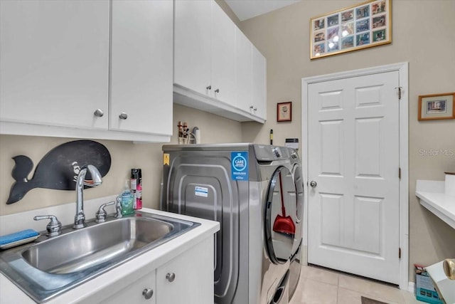 laundry area with cabinets, light tile patterned floors, sink, and washing machine and clothes dryer