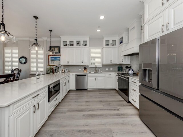 501 Tamiami Trl N Unit 502, Venice, FL 34285 - kitchen with a peninsula, custom exhaust hood, stainless steel appliances, pendant lighting, and backsplash