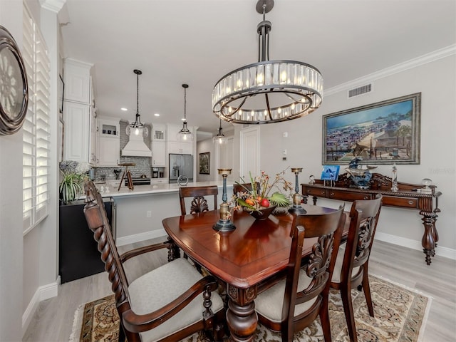 501 Tamiami Trl N Unit 502, Venice, FL 34285 - dining area with light wood finished floors, baseboards, visible vents, ornamental molding, and a notable chandelier