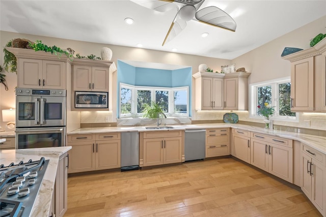 kitchen featuring tasteful backsplash, light wood-type flooring, stainless steel appliances, ceiling fan, and sink