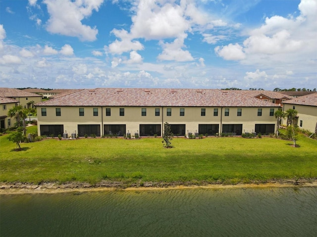 rear view of property with a water view and a lawn