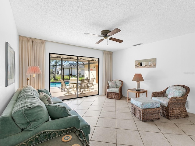 living room featuring ceiling fan, a textured ceiling, and light tile patterned floors