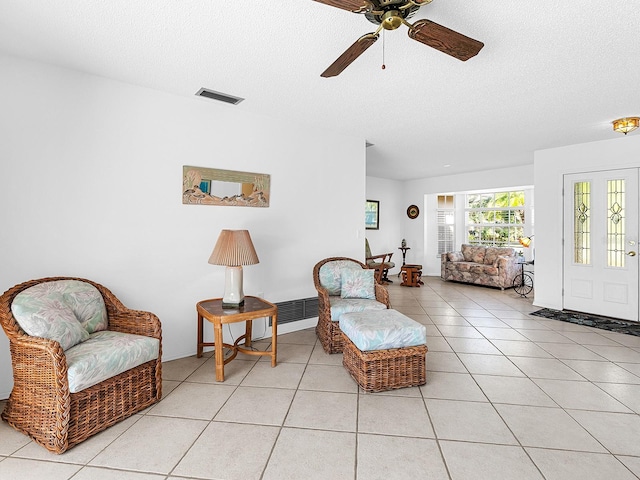 sitting room with ceiling fan, light tile patterned floors, and a textured ceiling