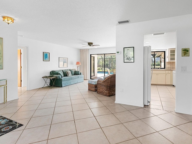 unfurnished living room with ceiling fan, a textured ceiling, and light tile patterned floors