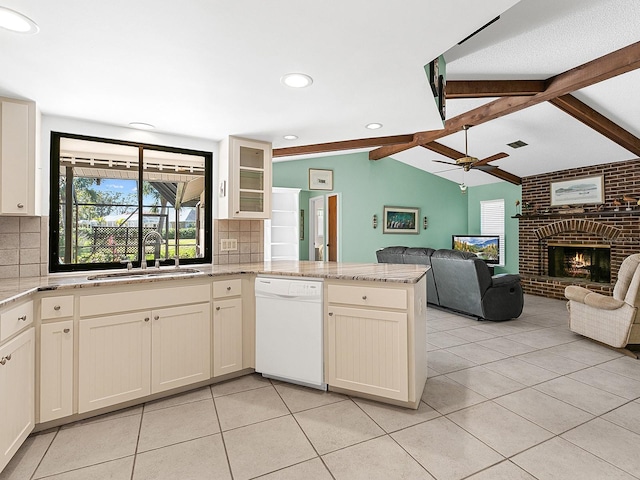 kitchen featuring sink, white dishwasher, a fireplace, lofted ceiling with beams, and kitchen peninsula