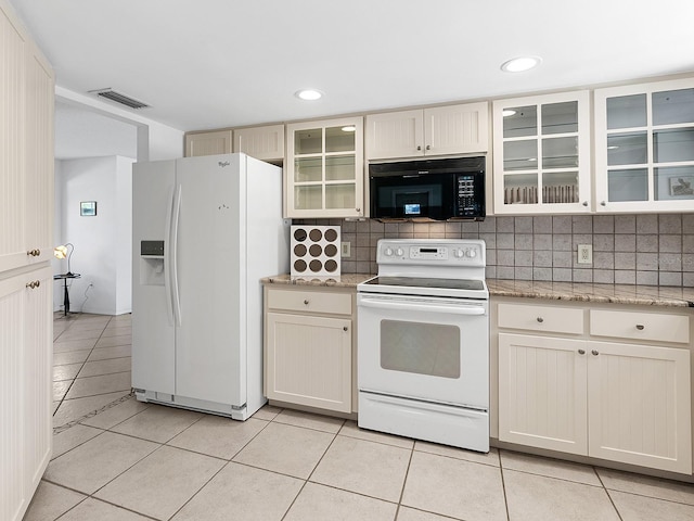 kitchen featuring tasteful backsplash, light stone countertops, light tile patterned floors, and white appliances