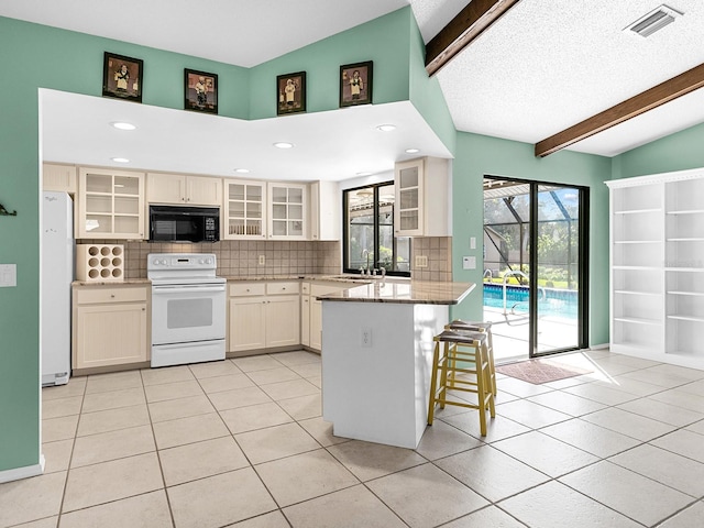 kitchen featuring tasteful backsplash, a kitchen bar, light tile patterned floors, light stone counters, and white appliances