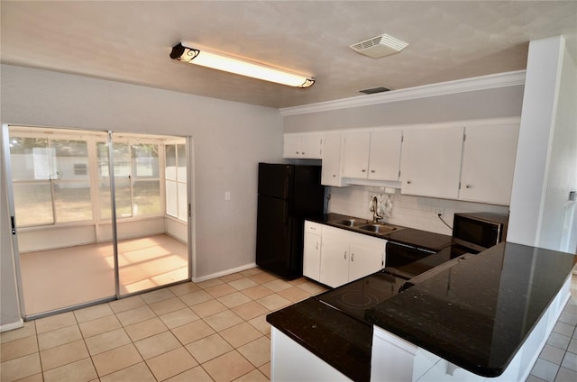 kitchen with sink, white cabinets, backsplash, dark stone counters, and black fridge