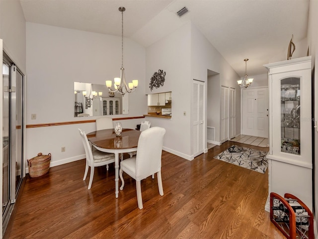 dining room with hardwood / wood-style floors, a notable chandelier, and high vaulted ceiling