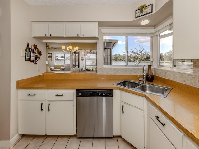 kitchen featuring dishwasher, sink, white cabinets, light tile patterned floors, and a textured ceiling