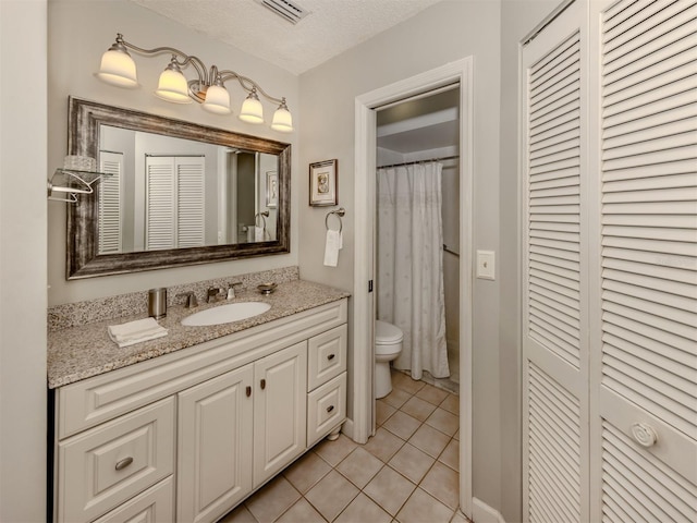 bathroom featuring tile patterned flooring, a shower with shower curtain, vanity, a textured ceiling, and toilet