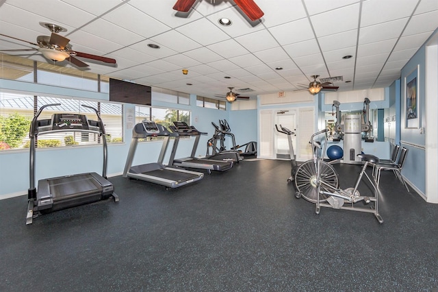 exercise room with ceiling fan, a paneled ceiling, and a healthy amount of sunlight