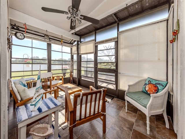 sunroom with ceiling fan and a water view