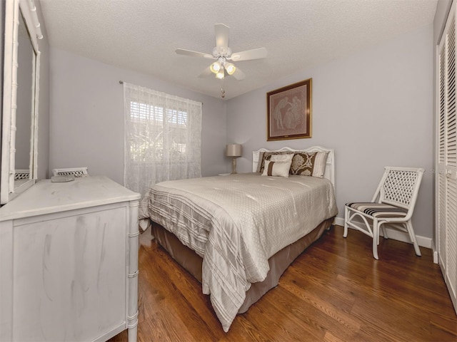 bedroom with dark wood-type flooring, ceiling fan, a closet, and a textured ceiling