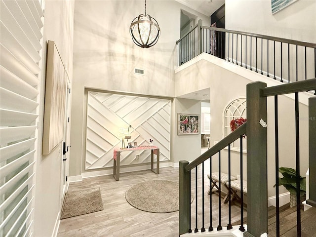 foyer entrance with a high ceiling, hardwood / wood-style floors, and an inviting chandelier