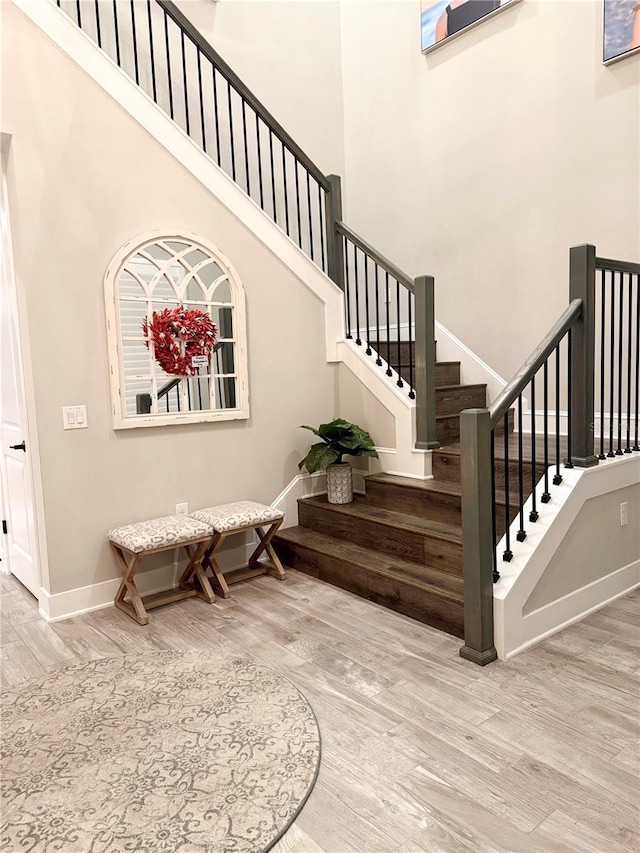 stairs with a towering ceiling and hardwood / wood-style floors