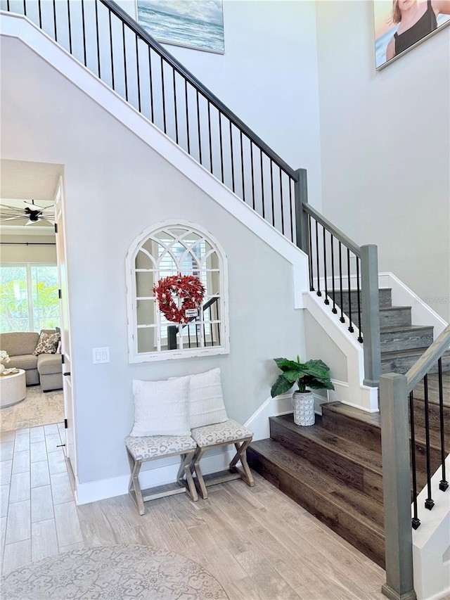 stairway featuring hardwood / wood-style floors, a towering ceiling, and ceiling fan