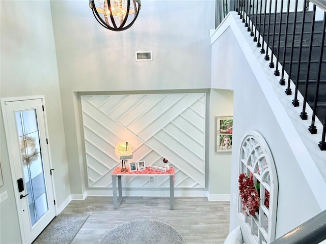 entrance foyer with a towering ceiling, a chandelier, and light wood-type flooring