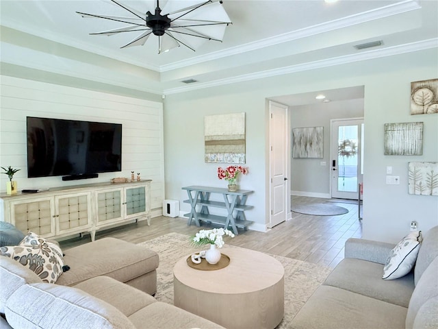 living room featuring crown molding, a raised ceiling, and light hardwood / wood-style flooring