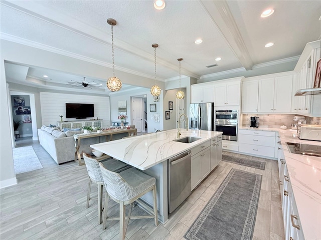 kitchen featuring sink, a center island with sink, stainless steel appliances, white cabinets, and a kitchen bar