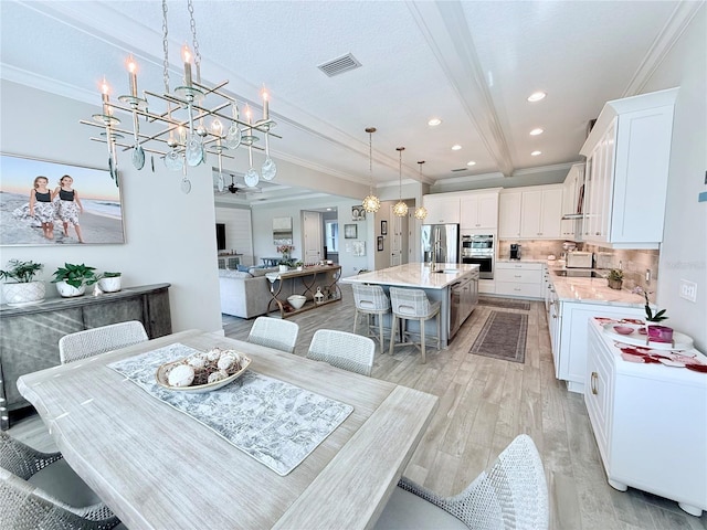 dining area with crown molding, light hardwood / wood-style floors, a chandelier, and beamed ceiling