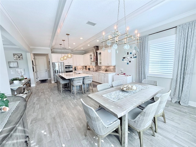 dining area featuring ornamental molding, sink, an inviting chandelier, and light wood-type flooring