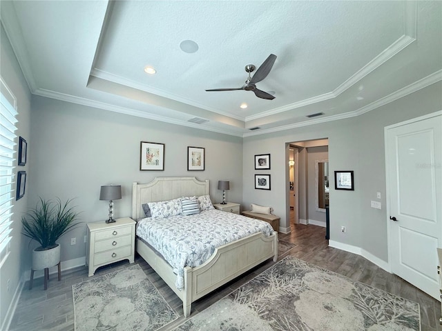 bedroom with a raised ceiling, crown molding, and hardwood / wood-style flooring